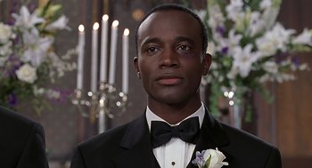 Movie still from “The Best Man” (1999), directed by Malcolm D. Lee – A man in a tuxedo with a flower in his lapel; Close Up shot, Over the shoulder angle
