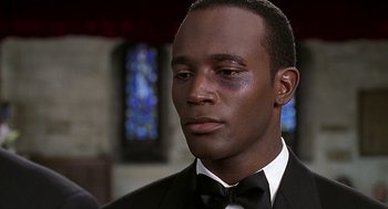 Movie still from “The Best Man” (1999), directed by Malcolm D. Lee – A person wearing a suit and a bow tie; Close Up shot, Over the shoulder angle