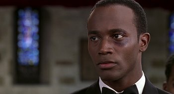 Movie still from “The Best Man” (1999), directed by Malcolm D. Lee – A person wearing a suit and a bow tie; Close Up shot, Over the shoulder angle