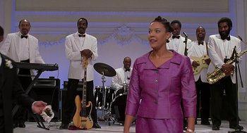 Movie still from “The Best Man” (1999), directed by Malcolm D. Lee – A woman in a purple dress standing in front of a group of men; Medium shot, Low angle