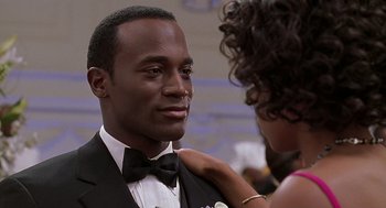 Movie still from “The Best Man” (1999), directed by Malcolm D. Lee – A man in a tuxedo is being hugged by a woman in a black dress; Close Up shot, Over the shoulder angle