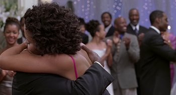 Movie still from “The Best Man” (1999), directed by Malcolm D. Lee – A man and a woman hugging in front of a group of people; Close Up shot, Over the shoulder angle