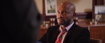 Movie still from “The Best Man Holiday” (2013), directed by Malcolm D. Lee – A man in a suit and tie looking at the camera; Close Up shot, Over the shoulder angle