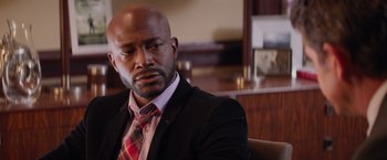 Movie still from “The Best Man Holiday” (2013), directed by Malcolm D. Lee – A man wearing a suit and tie sitting in a chair; Close Up shot, Over the shoulder angle