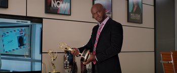 Movie still from “The Best Man Holiday” (2013), directed by Malcolm D. Lee – A man in a suit holding an emmy award; Medium shot, Low angle