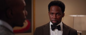 Movie still from “The Best Man Holiday” (2013), directed by Malcolm D. Lee – A man wearing a suit and bow tie in front of a painting; Close Up shot, Over the shoulder angle