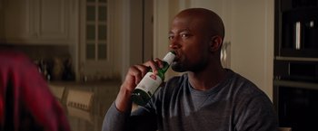 Movie still from “The Best Man Holiday” (2013), directed by Malcolm D. Lee – A man drinking a bottle of beer while sitting in a chair; Close Up shot, Over the shoulder angle