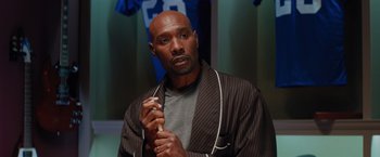 Movie still from “The Best Man Holiday” (2013), directed by Malcolm D. Lee – A bald man in a robe holding a pair of scissors; Close Up shot, High angle