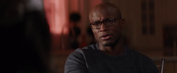 Movie still from “The Best Man Holiday” (2013), directed by Malcolm D. Lee – A bald man wearing glasses and a gray shirt; Close Up shot, Over the shoulder angle