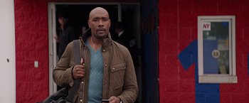 Movie still from “The Best Man Holiday” (2013), directed by Malcolm D. Lee – A man in a brown jacket is holding a phone; Medium shot, Over the shoulder angle