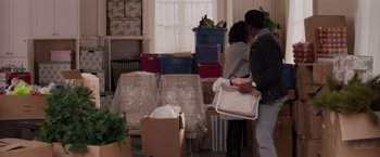 Movie still from “The Best Man Holiday” (2013), directed by Malcolm D. Lee – Two people moving boxes in a room with boxes stacked on top of each other; Wide shot, Over the shoulder angle