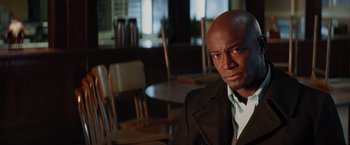 Movie still from “The Best Man Holiday” (2013), directed by Malcolm D. Lee – A man sitting in a chair in front of a table; Close Up shot, Over the shoulder angle