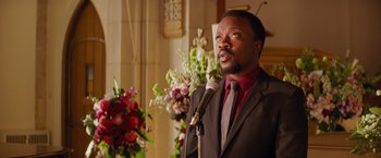 Movie still from “The Best Man Holiday” (2013), directed by Malcolm D. Lee – A man in a suit and tie is speaking into a microphone; Close Up shot, High angle
