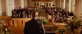 Movie still from “The Best Man Holiday” (2013), directed by Malcolm D. Lee – A man standing in front of a bunch of people in front of a casket; Wide shot, High angle