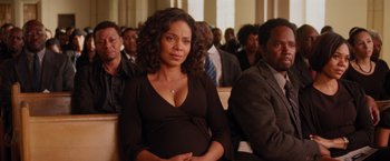 Movie still from “The Best Man Holiday” (2013), directed by Malcolm D. Lee – A woman in a black dress sitting in front of a crowd; Medium shot, High angle