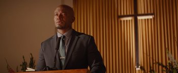 Movie still from “The Best Man Holiday” (2013), directed by Malcolm D. Lee – A man standing at a podium in front of a microphone; Close Up shot, Low angle