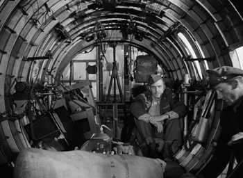 Movie still from “The Best Years of Our Lives” (1946), directed by William Wyler – A man sitting inside of an airplane surrounded by junk; Wide shot, High angle