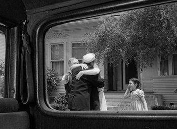 Movie still from “The Best Years of Our Lives” (1946), directed by William Wyler – A black - and - white photo of two men hugging in front of a house; Wide shot, Over the shoulder angle