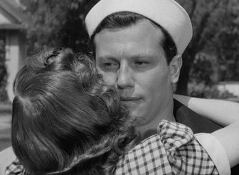 Movie still from “The Best Years of Our Lives” (1946), directed by William Wyler – A man in a sailor's hat is kissing a woman; Close Up shot, Over the shoulder angle