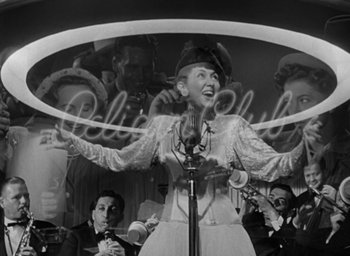 Movie still from “The Best Years of Our Lives” (1946), directed by William Wyler – An old photo of a woman singing into a microphone; Medium shot, Low angle