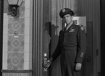 Movie still from “The Best Years of Our Lives” (1946), directed by William Wyler – A man in uniform standing in front of a building; Medium shot, Low angle