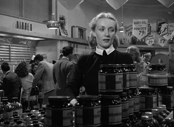 Movie still from “The Best Years of Our Lives” (1946), directed by William Wyler – A woman standing in front of a counter filled with jars; Medium shot, Low angle