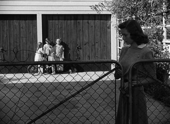 Movie still from “The Best Years of Our Lives” (1946), directed by William Wyler – A woman standing in front of a fence with two other women; Wide shot, Low angle