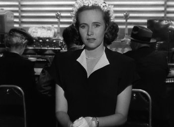 Movie still from “The Best Years of Our Lives” (1946), directed by William Wyler – A woman in a black dress with a flower crown; Medium shot, Low angle