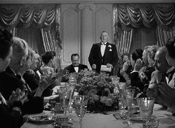 Movie still from “The Best Years of Our Lives” (1946), directed by William Wyler – A group of people sitting at a table with wine glasses; Wide shot, Low angle