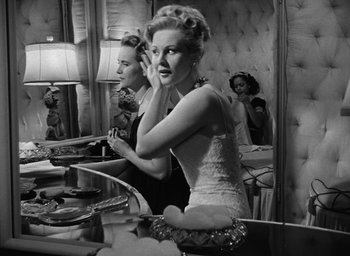 Movie still from “The Best Years of Our Lives” (1946), directed by William Wyler – A woman in a white dress in front of a mirror; Medium shot, Low angle