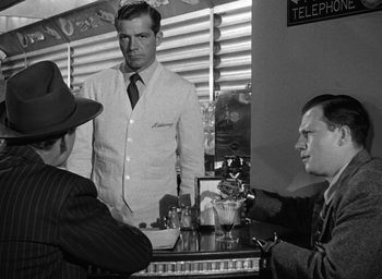 Movie still from “The Best Years of Our Lives” (1946), directed by William Wyler – Three men sitting at a table in front of a man in a white suit; Medium shot, Over the shoulder angle