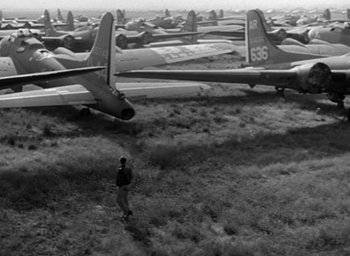 Movie still from “The Best Years of Our Lives” (1946), directed by William Wyler – A man standing in front of a field of airplanes; Extreme Wide shot, High angle