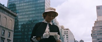 Movie still from “The Best of Everything” (1959), directed by Jean Negulesco – A woman wearing a hat and gloves holding a piece of paper in her hands; Medium shot, Low angle