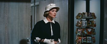 Movie still from “The Best of Everything” (1959), directed by Jean Negulesco – A woman wearing a white hat and white gloves; Medium shot, Over the shoulder angle