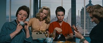 Movie still from “The Best of Everything” (1959), directed by Jean Negulesco – Two women sitting at a table with a bell in front of them; Medium shot, High angle