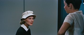 Movie still from “The Best of Everything” (1959), directed by Jean Negulesco – A woman wearing a white hat and a black dress; Close Up shot, Over the shoulder angle