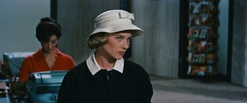 Movie still from “The Best of Everything” (1959), directed by Jean Negulesco – A woman wearing a white hat and a black dress; Close Up shot, Over the shoulder angle
