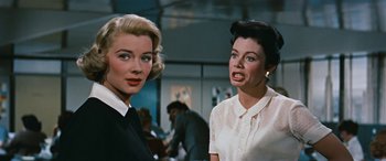 Movie still from “The Best of Everything” (1959), directed by Jean Negulesco – Two women standing next to each other in a room; Close Up shot, Low angle