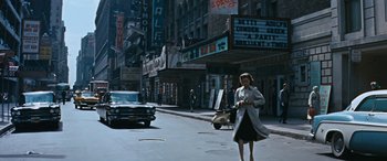 Movie still from “The Best of Everything” (1959), directed by Jean Negulesco – A woman walking down a street near a movie theater; Extreme Wide shot, High angle