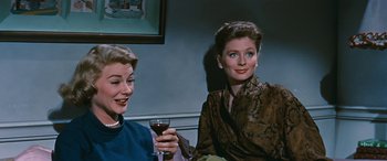 Movie still from “The Best of Everything” (1959), directed by Jean Negulesco – Two women sitting next to each other holding a glass of red wine; Medium shot, Low angle