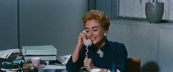Movie still from “The Best of Everything” (1959), directed by Jean Negulesco – An older woman talking on a phone while sitting at a desk; Close Up shot, High angle