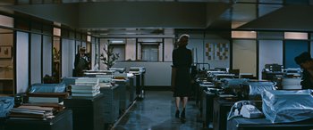 Movie still from “The Best of Everything” (1959), directed by Jean Negulesco – A woman is walking in a dark office; Wide shot, High angle