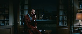 Movie still from “The Best of Everything” (1959), directed by Jean Negulesco – A man sitting on a chair talking on a phone; Medium shot, High angle