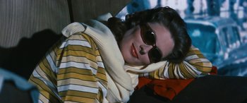 Movie still from “The Best of Everything” (1959), directed by Jean Negulesco – A woman wearing sunglasses and a striped shirt; Medium shot, High angle
