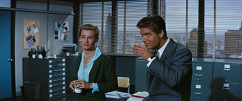 Movie still from “The Best of Everything” (1959), directed by Jean Negulesco – A man and a woman sitting at a table drinking from cups; Medium shot, Low angle