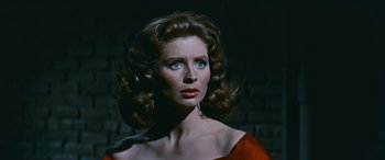 Movie still from “The Best of Everything” (1959), directed by Jean Negulesco – A woman in a red dress with blue eyes looking to her left; Close Up shot, Low angle