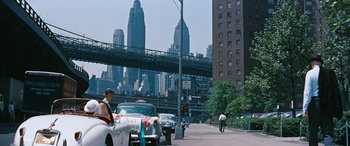 Movie still from “The Best of Everything” (1959), directed by Jean Negulesco – A man standing next to a car on the side of a road; Extreme Wide shot, Over the shoulder angle