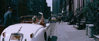 Movie still from “The Best of Everything” (1959), directed by Jean Negulesco – A woman driving a car down a street; Wide shot, Over the shoulder angle