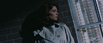 Movie still from “The Best of Everything” (1959), directed by Jean Negulesco – A woman wearing a trench coat standing next to a brick wall; Close Up shot, Low angle