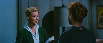 Movie still from “The Best of Everything” (1959), directed by Jean Negulesco – Two women are talking to each other in front of a mirror; Medium shot, Over the shoulder angle